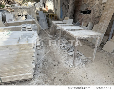 Marble slabs and dusty workspace with stone debris in outdoor workshop setting 139064685