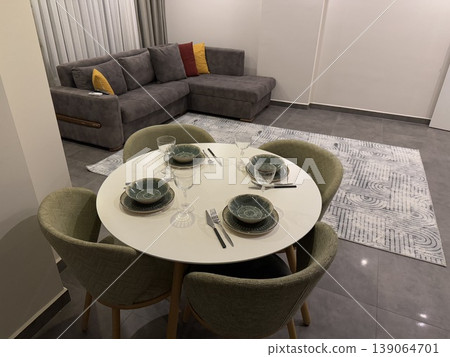 Modern dining area with set table and gray sofa background in a contemporary living room 139064701