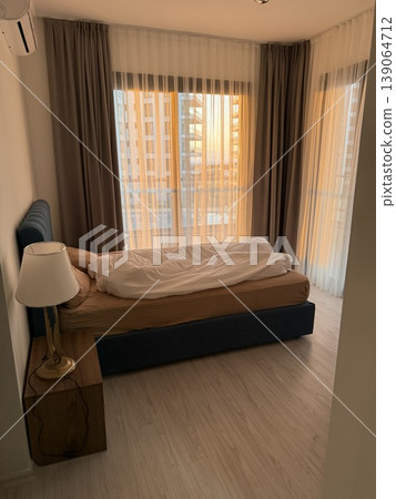Cozy bedroom with unmade bed and soft morning light filtering through curtains, perfect for backgrounds Cozy bedroom with unmade bed and soft morning light filtering through curtains, perfect for backgrounds 139064712