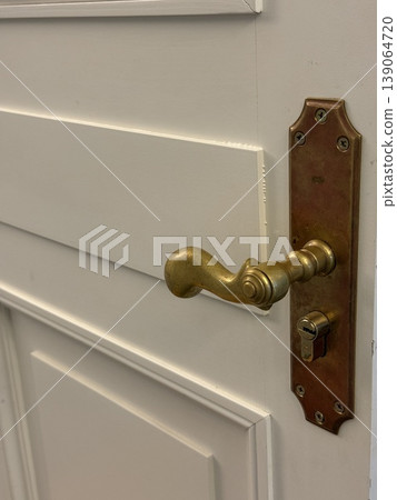 Antique brass door knocker on rustic wooden door, offering vintage charm and historical appeal Antique brass door knocker on rustic wooden door, offering vintage charm and historical appeal 139064720