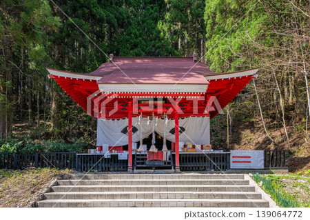 Gozaishi Shrine on the shores of Lake Tazawa in Akita: A vibrant vermilion shrine building stands out against the lush green forest. 139064772