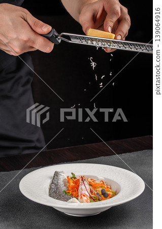 Chef grating cheese over gourmet seafood dish fine dining plating process 139064916