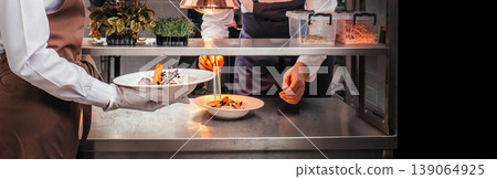 Chef plating gourmet dish and waiter serving in professional restaurant kitchen Chef plating gourmet dish and waiter serving in professional restaurant kitchen 139064925