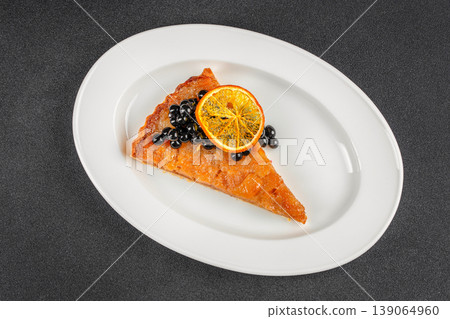 Cake slice with berries and dried orange on white plate angled view dessert plating 139064960