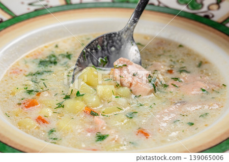 Salmon soup with potatoes and spoon close up 139065006