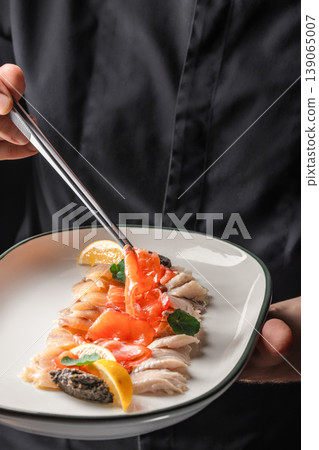 Hand holding fish with salmon slices seafood plating action 139065007