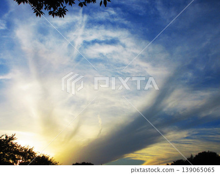 A scene of a sunset sky with strangely shaped clouds spreading across it. A scene of a sunset sky with strangely shaped clouds spreading across it. 139065065