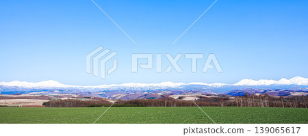 A spring landscape viewed from the hills of Biei, where mountains and a refreshing blue sky stretch out. 139065617