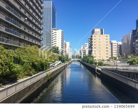 A city river and tree-lined streets under a blue sky, a modern Japanese cityscape. A city river and tree-lined streets under a blue sky, a modern Japanese cityscape. 139065694