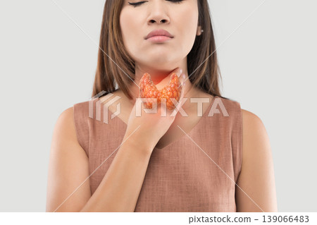 A woman holding her throat, illustrating potential thyroid pathology. 139066483