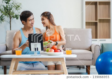 Fit couple enjoys healthy fruit breakfast after yoga training. fitness, nutrition, home lifestyle. Fit couple enjoys healthy fruit breakfast after yoga training. fitness, nutrition, home lifestyle. 139066955