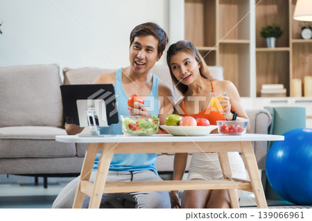 Fit couple enjoys healthy fruit breakfast after yoga training. fitness, nutrition, home lifestyle. Fit couple enjoys healthy fruit breakfast after yoga training. fitness, nutrition, home lifestyle. 139066961