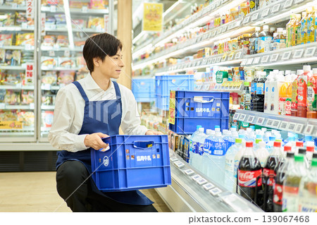 A man arranging merchandise on display. A man arranging merchandise on display. 139067468
