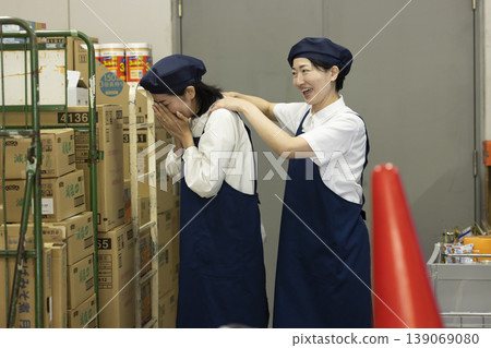 A colleague comforts a woman who is crying in the back room. A colleague comforts a woman who is crying in the back room. 139069080