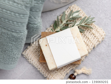 Beige solid soap bar with blank label mockup near with leaves and sage green bath towel 139069201