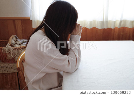 A woman, with her hair unkempt and still in her loungewear, hangs her head listlessly. A woman, with her hair unkempt and still in her loungewear, hangs her head listlessly. 139069233