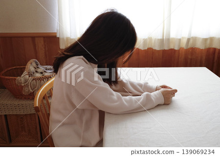 A woman, with her hair unkempt and still in her loungewear, hangs her head listlessly. A woman, with her hair unkempt and still in her loungewear, hangs her head listlessly. 139069234