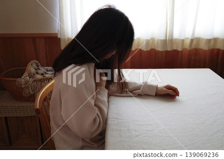 一位頭髮蓬亂、身穿家居服的女子無精打采地低著頭。 一位頭髮蓬亂、身穿家居服的女子無精打采地低著頭。 139069236
