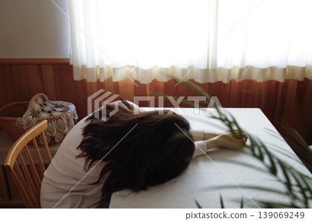 一個女人頭髮蓬亂,還穿著睡衣,無精打采地癱坐在地上。 一個女人頭髮蓬亂,還穿著睡衣,無精打采地癱坐在地上。 139069249
