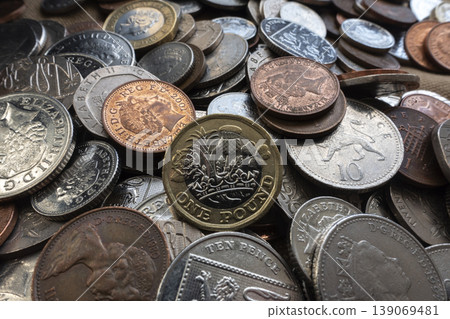 Mixed UK coins scattered on table with one pound coin in the middle, money and savings concept 139069481