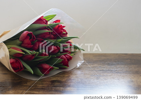Bouquet of tulips in wrapping placed on table near window 139069499