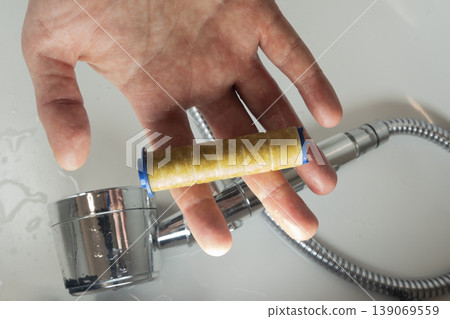 Hand holding old rusty shower filter during water filter replacement process Hand holding old rusty shower filter during water filter replacement process 139069559
