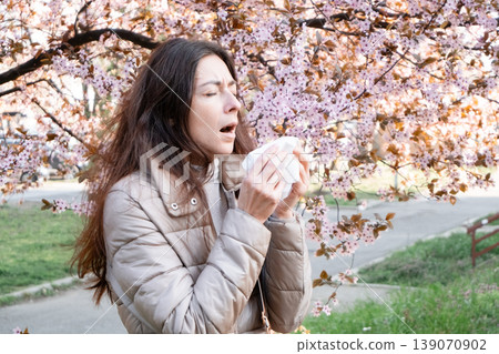 Side view of a woman sneezing into a tissue. Spring pollen allergy, hay fever sufferer, seasonal sickness. Side view of a woman sneezing into a tissue. Spring pollen allergy, hay fever sufferer, seasonal sickness. 139070902