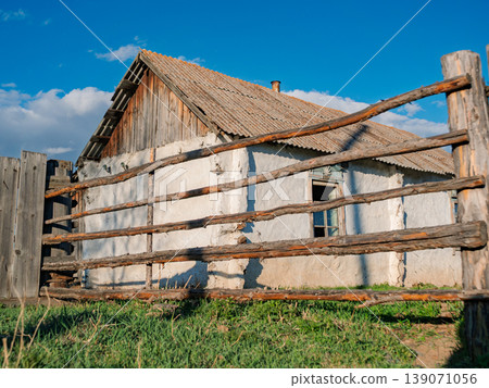 Old farmhouse with wooden fence in rural area under blue sky in daylight Old farmhouse with wooden fence in rural area under blue sky in daylight 139071056