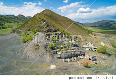Aerial view of an old mining site with abandoned buildings and overgrown landscape in countryside Aerial view of an old mining site with abandoned buildings and overgrown landscape in countryside 139071071