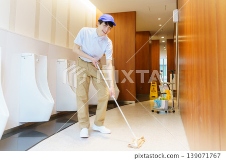 A young Japanese male cleaner wipes the floor of a restroom in an office building. Photo courtesy of Denpa Gakuen Tokyo Electronics College. A young Japanese male cleaner wipes the floor of a restroom in an office building. Photo courtesy of Denpa Gakuen Tokyo Electronics College. 139071767