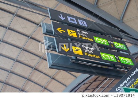 Directional signage for airport gates C38, C39, and C40 with clear arrows and multilingual text in a modern terminal environment 139071914