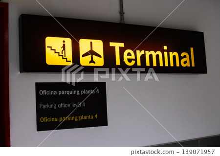 Terminal sign indicating stairs and airplane icon, with multilingual text for parking office level 4 in a modern airport setting 139071957