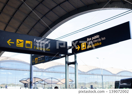 Airport signage indicating check-in and public bus services with clear directional arrows and modern architectural elements in the background Airport signage indicating check-in and public bus services with clear directional arrows and modern architectural elements in the background 139072002
