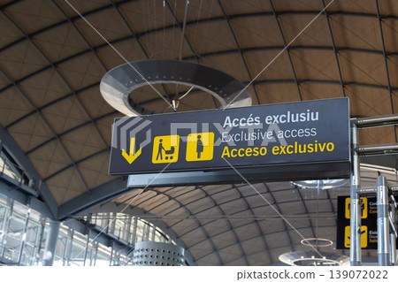Sign indicating exclusive access with multilingual text and directional arrows inside a modern airport terminal Sign indicating exclusive access with multilingual text and directional arrows inside a modern airport terminal 139072022