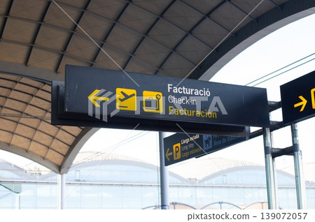 Airport signage indicating check-in direction with icons for flight and luggage under a modern architectural structure Airport signage indicating check-in direction with icons for flight and luggage under a modern architectural structure 139072057