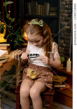 Girl sitting at table looking through magnifying glass at duck bird, curious child learning through play Girl sitting at table looking through magnifying glass at duck bird, curious child learning through play 139072609