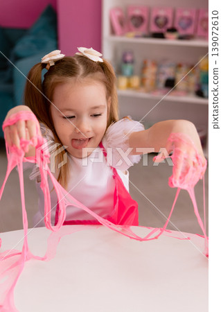 Little girl playing with pink slime indoors, creative sensory activity for children Little girl playing with pink slime indoors, creative sensory activity for children 139072610