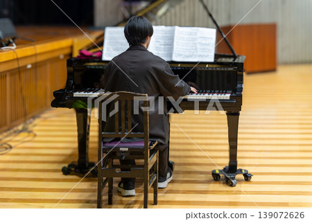 A man playing a grand piano 139072626