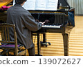 A man playing a grand piano 139072627