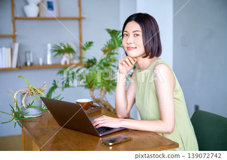 A portrait of a businesswoman smiling while using a laptop. A portrait of a businesswoman smiling while using a laptop. 139072742