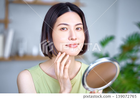 一位美麗的亞洲女性在護膚過程中對著鏡子檢查自己的皮膚。 一位美麗的亞洲女性在護膚過程中對著鏡子檢查自己的皮膚。 139072765
