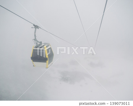 Cable car journey through dense mountain fog, with other gondolas barely visible in the distance Cable car journey through dense mountain fog, with other gondolas barely visible in the distance 139073011