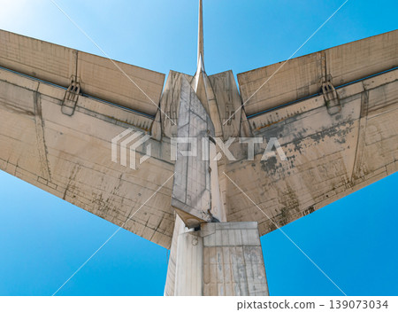 A close up upward view shows the dirty and aged underside of an airplane's horizontal and vertical tail stabilizers set against a blue sky. 139073034