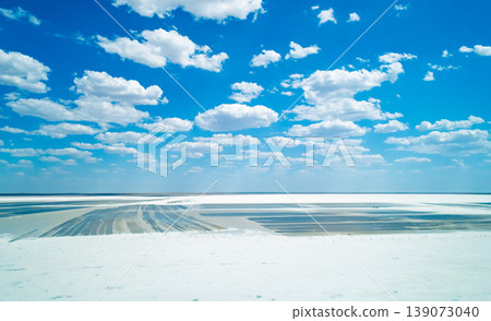 Expansive salt landscape at Baskunchak lake with distinct mining patterns under a bright blue sky and scattered white clouds 139073040