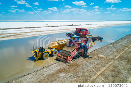 Aerial view captures heavy machinery operates on Lake Baskunchak extracting salt during a clear day mining operation Aerial view captures heavy machinery operates on Lake Baskunchak extracting salt during a clear day mining operation 139073041