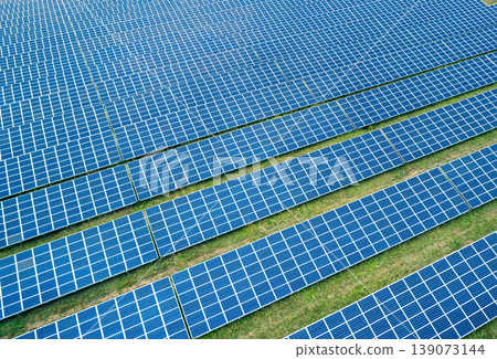 Aerial view of vast solar farm with numerous photovoltaic panels stretching across rural landscape 139073144