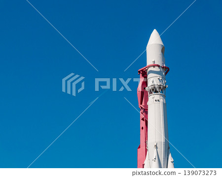 Towering white and red rocket display under clear blue sky with a distant jet contrail Towering white and red rocket display under clear blue sky with a distant jet contrail 139073273