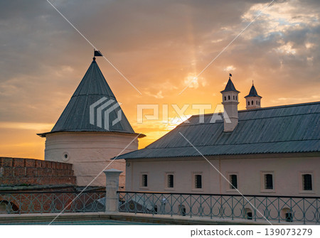 Kazan Kremlin's grand tower and historic building under a vibrant golden sunset sky Kazan Kremlin's grand tower and historic building under a vibrant golden sunset sky 139073279