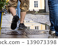 Closeup of men legs walking on a wet cobblestone street after rain, reflecting city architecture and urban lifestyle in Tallinn, Estonia, old town. Movement, footwear, rainy weather concept 139073398