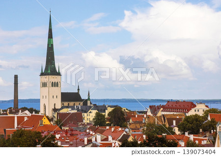 Panoramic view of Tallinn, capital of Estonia, showcasing historic architecture, medieval churches, red rooftops, and the Baltic sea in the background. Aerial view of old town. St. Olaf church tower 139073404
